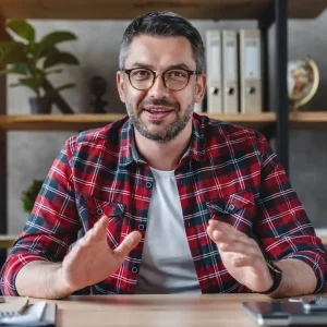 smiling-young-businessman-sit-at-desk-talk-on-webcam-having-video-call-or-conversation-with-client.webp