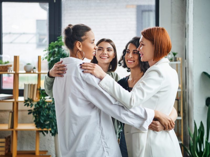 overjoyed-multiethnic-women-and-redhead-motivation-coach-hugging-and-looking-at-each-other-e1694367472878.jpg