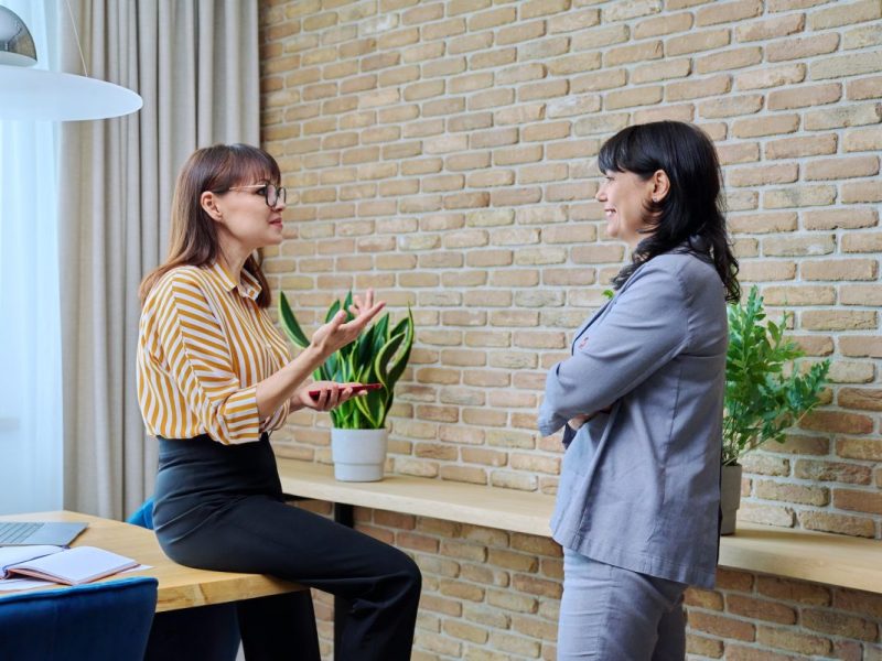 two-mature-business-women-are-talking-in-a-modern-office--e1694367459151.jpg