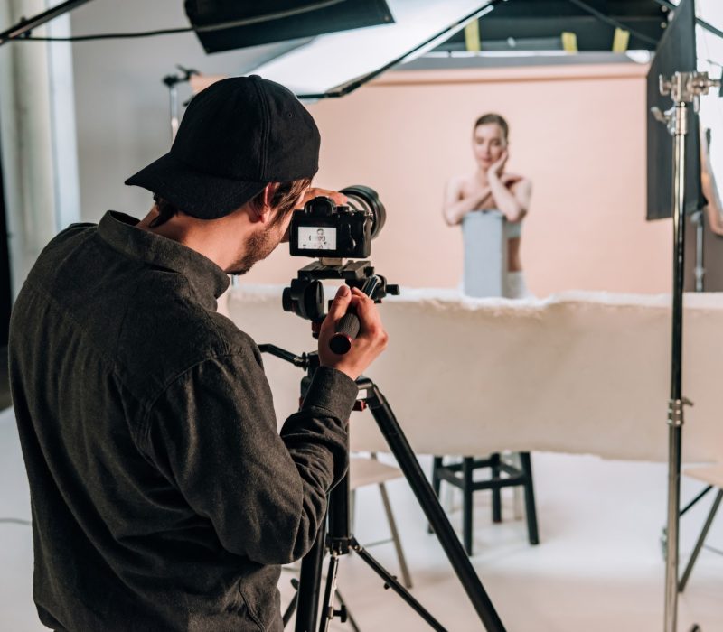 selective-focus-of-cameraman-filming-beautiful-model-in-photo-studio-with-spotlights.jpg