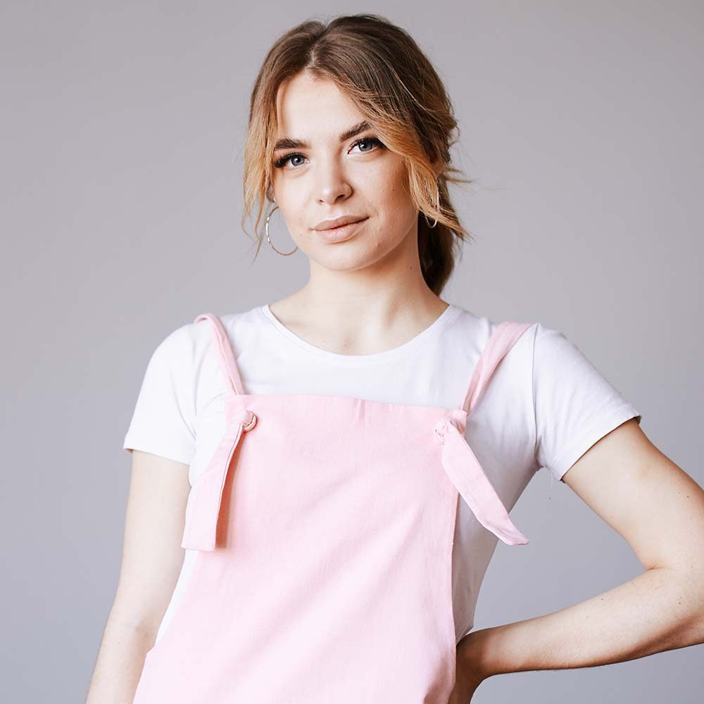 A woman in a pink in work clothes on a gray background is looking at the camera Renovation and new life for old things. Brushes and roller. Self-repair. Professional help.